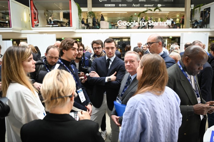 Bardella sta con le braccia conserte in mezzo a un gruppo di persone