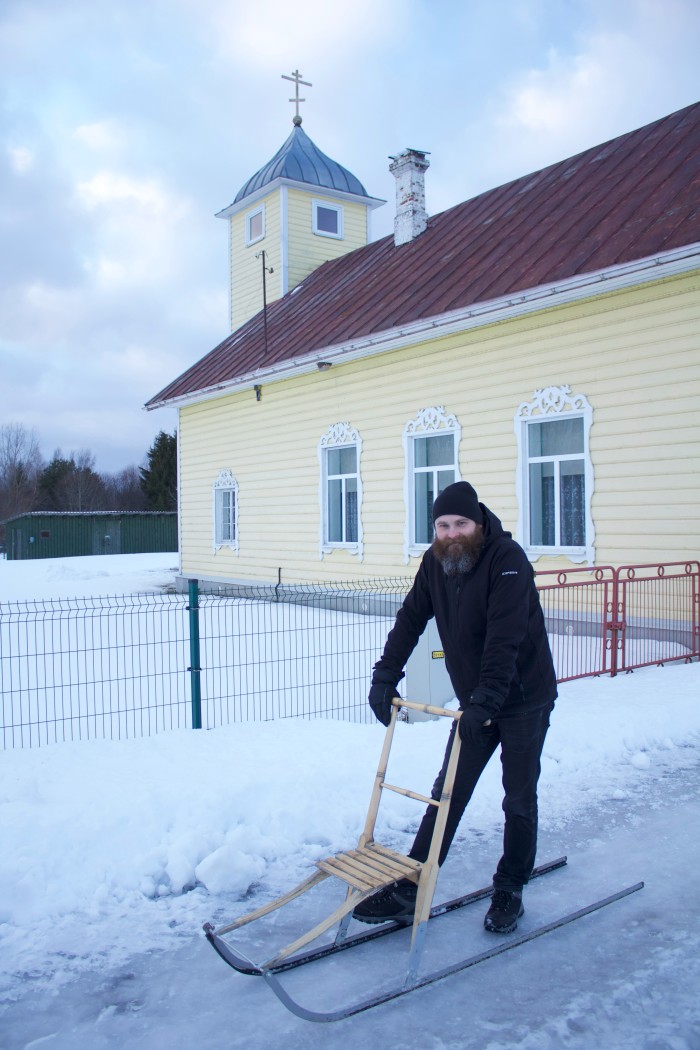 Un uomo sta fuori da una chiesa con una slitta per attraversare il ghiaccio