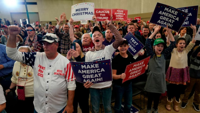 Il pubblico ad un caucus a Waterloo, Iowa, reagisce mentre parla Donald Trump