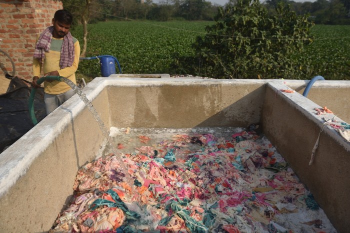 Una persona versa acqua da un tubo in un'enorme vasca di materiale tessile