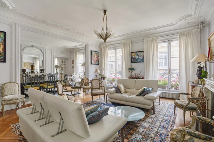 Luminoso ed elegante soggiorno di un appartamento parigino, illuminato dalla luce del sole proveniente da tre finestre a tutta altezza 