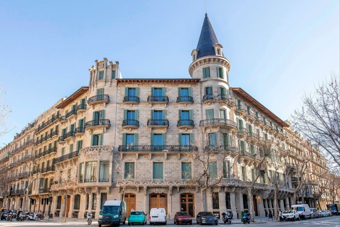 All'esterno di un grande edificio a Barcellona, ​​con molte stanze e una torretta in stile castello che si erge dalla parte superiore sinistra della struttura