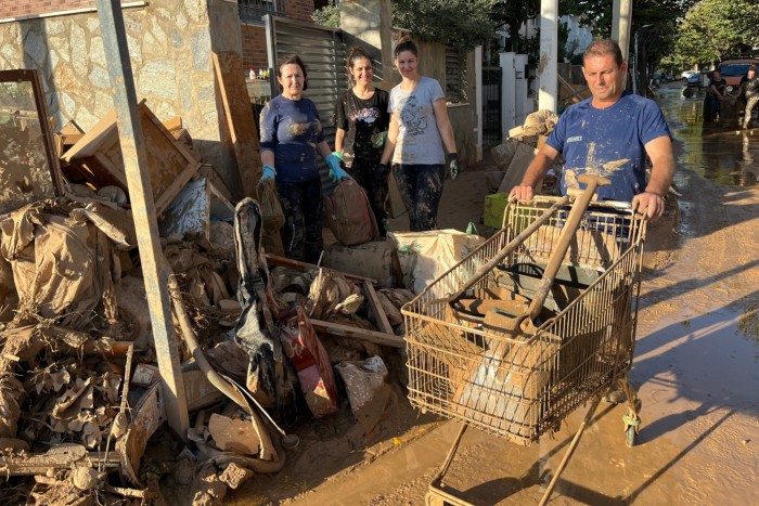 Un uomo con un carrello della spesa pieno di attrezzi, accanto a mucchi di detriti