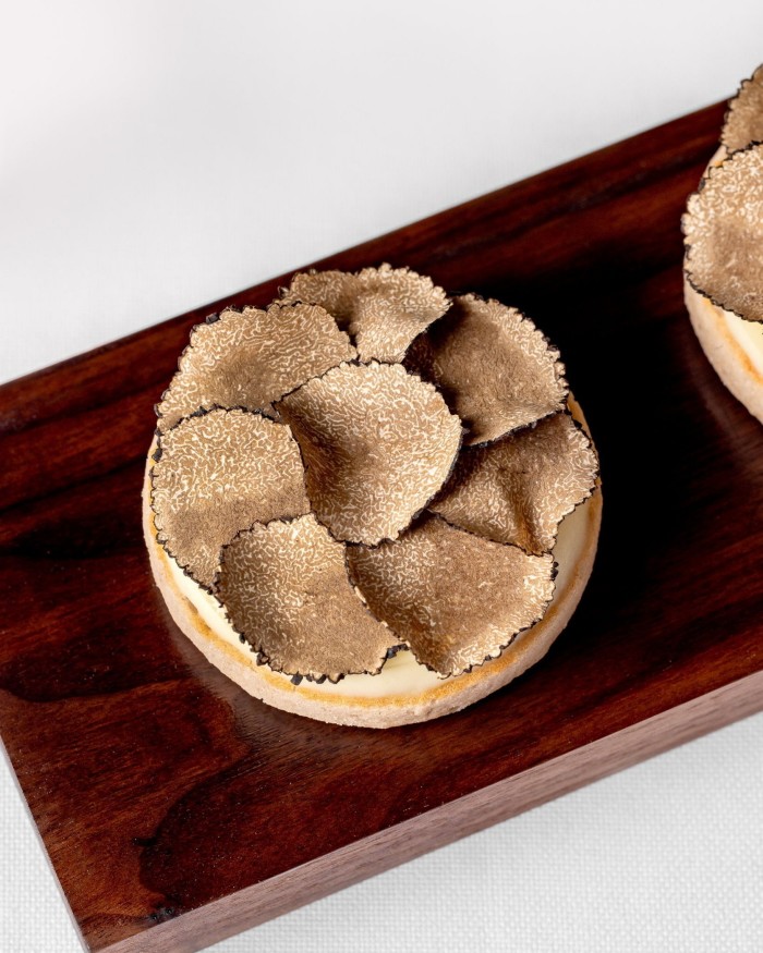 Tartufi freschi su focaccine su un piattino su una tavola di legno scuro al Claridge's