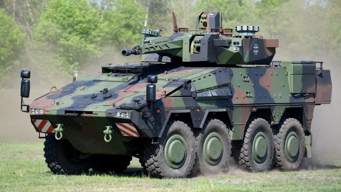 A Boxer armoured transport vehicle in camouflage colours manoeuvres on a dirt field
