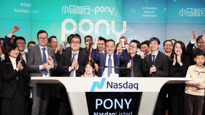 James Peng and other company figures stand behind a podium that reads ‘Nasdaq’ and ‘Pony’ while cheering and applauding