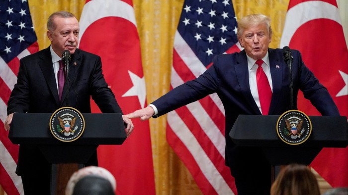 Donald Trump and Recep Tayyip Erdoğan standing at podiums, with Trump touching Erdoğan ‘s hand