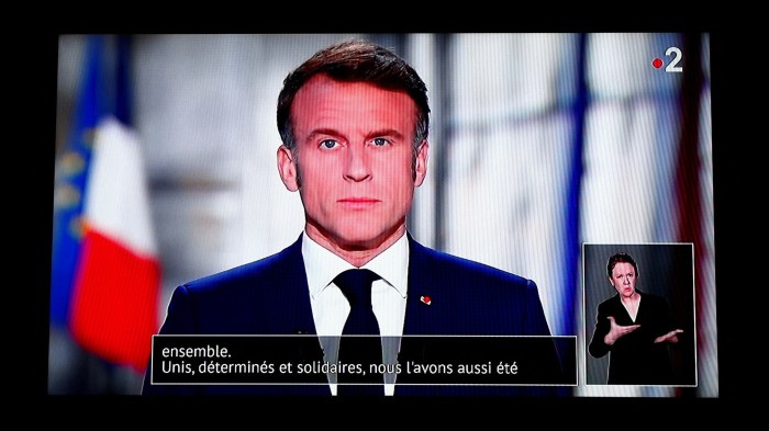 French President Emmanuel Macron is seen on a television screen as he delivers his New Year’s speech to the nation at the Elysee Palace