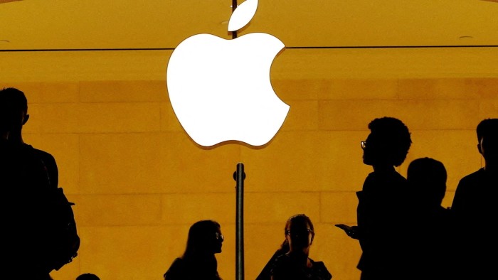 Customers walk past an Apple logo in an Apple store