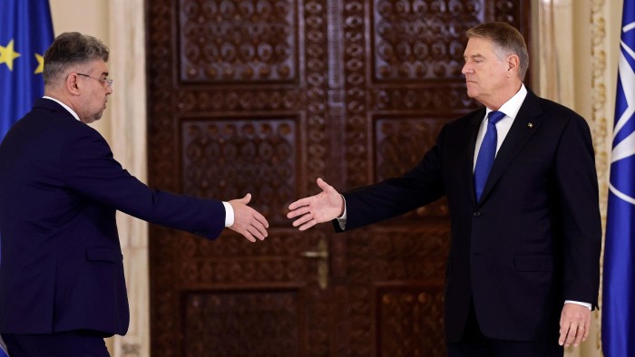 Romania’s Prime Minister Marcel Ciolacu, left, shakes hands with President Klaus Iohannis on Monday