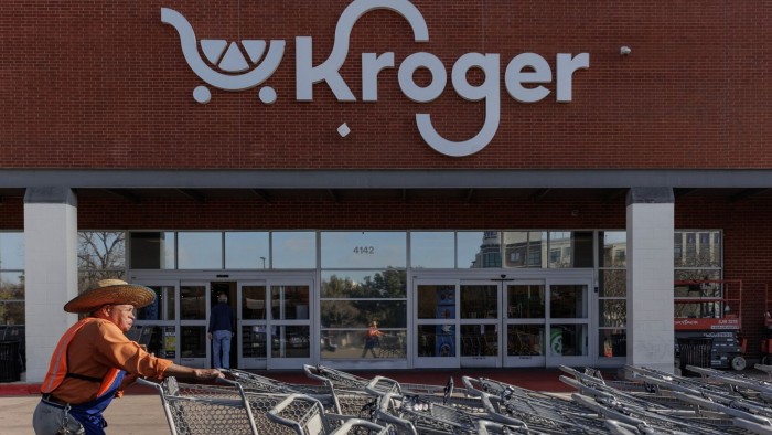 A worker pushes shopping carts outside a Kroger grocery store in Dallas, Texas