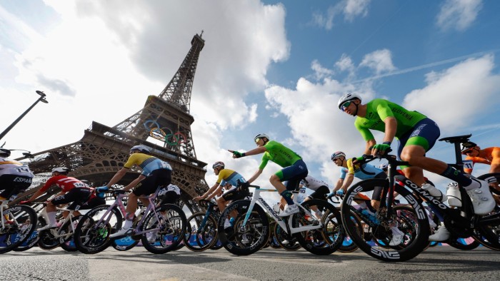 Athletes bike past the Eiffel Tower at the start of the men’s cycling road race during the Paris Olympics in August
