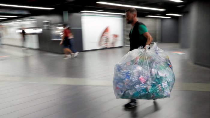 A worker holds a big plastic bag full of plastic bottles in San Giovanni metro station in Rome, Italy