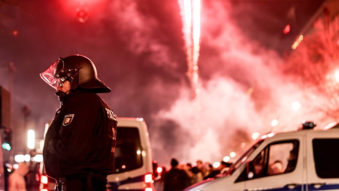 Fireworks illuminate the sky behind a police officer during New Year’s Eve celebrations in Berlin, Germany