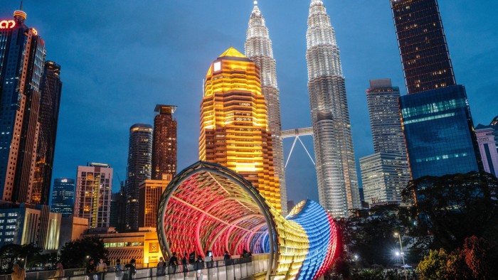 Skyscrapers and modern office buildings illuminated at night in Kuala Lumpur's business district.