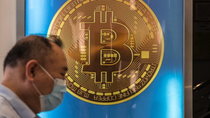 A man walks past a bitcoin poster