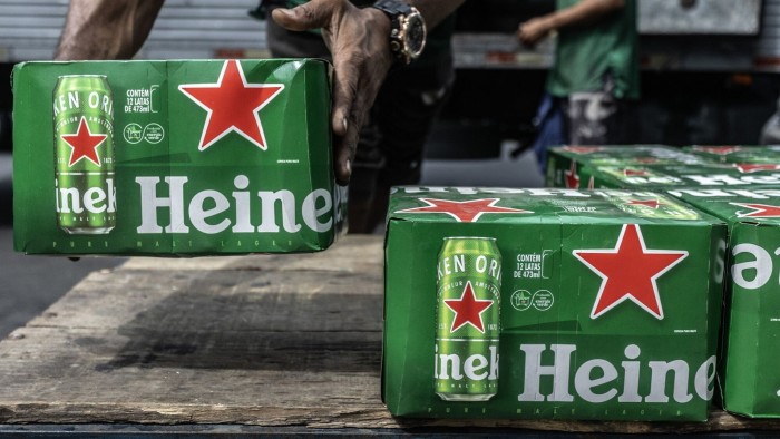 Delivery workers are unloading green cases of Heineken beer from a truck.