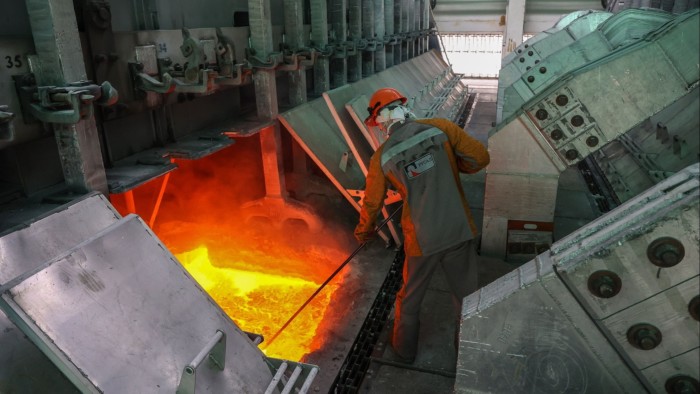 A worker in protective gear is removing slag from an electrolysis bath at an aluminium smelter in Russia.
