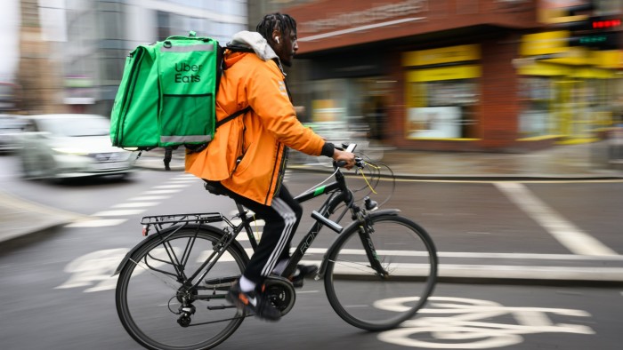 A Deliveroo worker delivering groceries on a bike