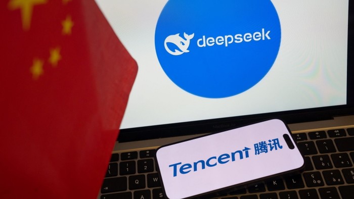 Tencent’s logo on the screen of a smartphone in front of a laptop with DeepSeek’s logo on its screen, with both devices next to a Chinese flag