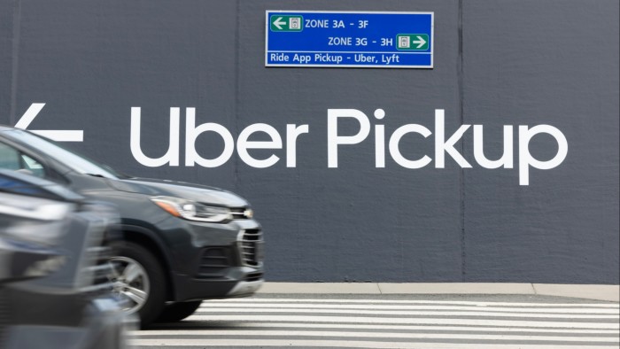 Vehicles drive past a large sign directing toward an Uber pickup location at Washington Dulles International Airport in Virginia