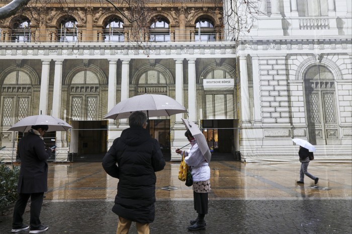 Pedoni sotto la pioggia fuori dalla borsa di Francoforte