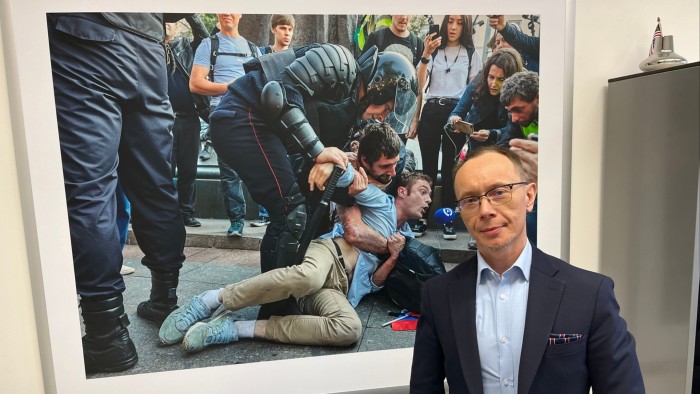RFE/RL’s Russian language-TV channel director Pavel Butorin standing in front of a large photo of protesters being arrested at a demonstration in August 2019 in Moscow, Russia