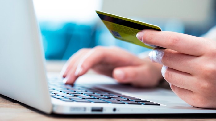 Hands typing on laptop keyboard while holding a credit card