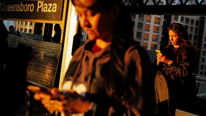 Pedestrians on their phones at Queensboro Plaza station in New York