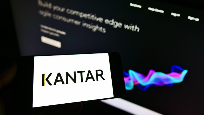 Person holding smartphone with logo of British market research company Kantar on the screen