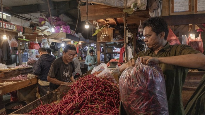 A shopkeeper packs chilli peppers at a market in Jakarta, Indonesia