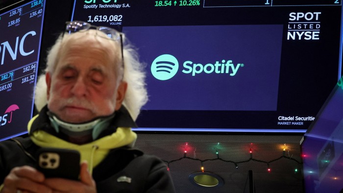 A screen displays the logo and trading information for Spotify on the floor of the New York Stock Exchange