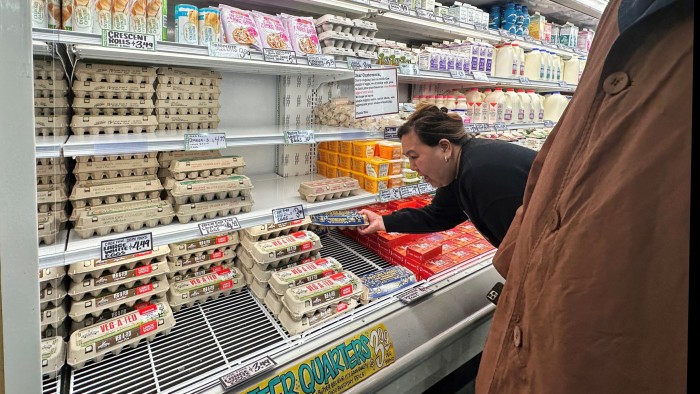 A shopper reaches for a carton of eggs at a grocery store