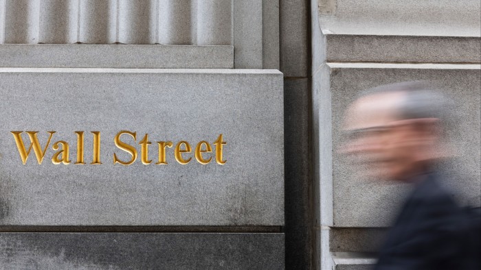 A pedestrian walks past a Wall Street sign near the New York Stock Exchange in New York