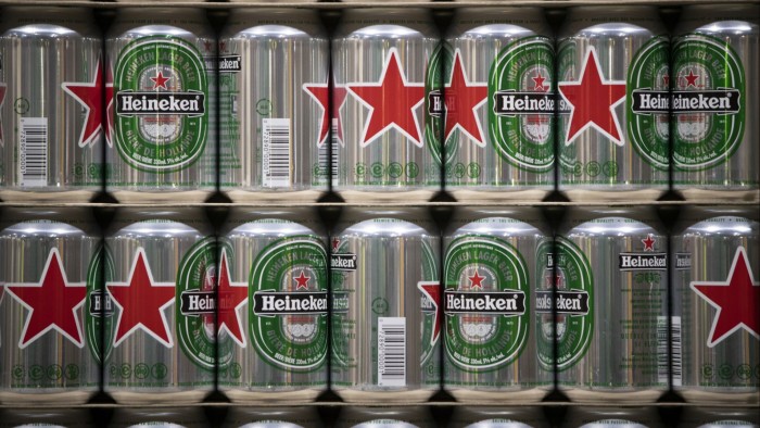 Heineken beer cans are stacked with their distinctive red star logos prominently displayed