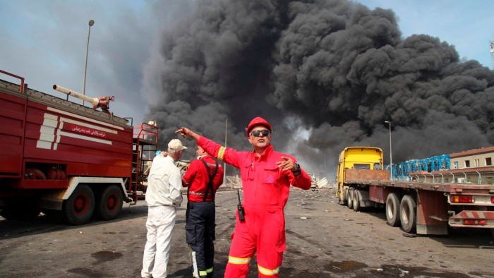 Firefighters work as black smoke rises over the port near the southern city of Bandar Abbas