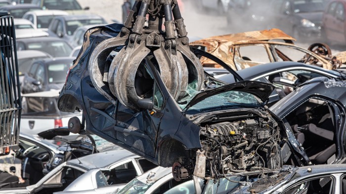 A crane lifting a vehicle for destruction at a recycling plant