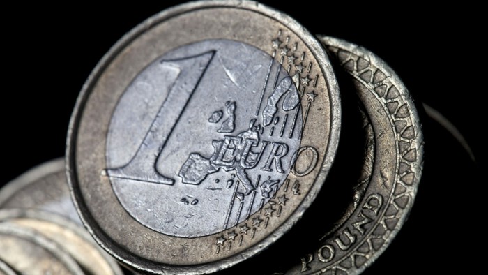 A one euro coin sits on top of a one pound coin in this arranged photograph in London