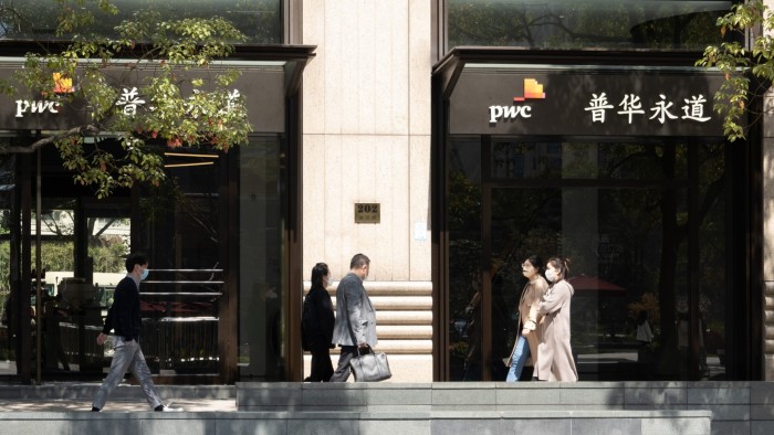 Exterior of the PwC building in Shanghai, with several people walking past the entrance and some wearing masks. The building's signage includes the PwC logo and its Chinese name
