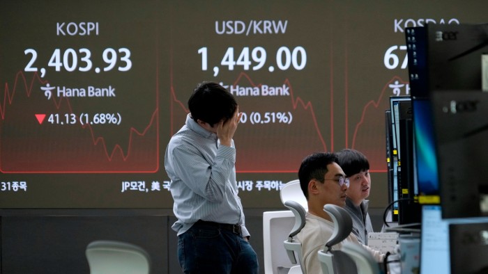 Trader holds his head in front of screens showing currency prices