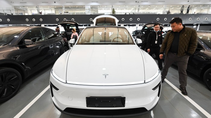 People are examining Tesla Model Y cars at the Tesla delivery centre in Beijing