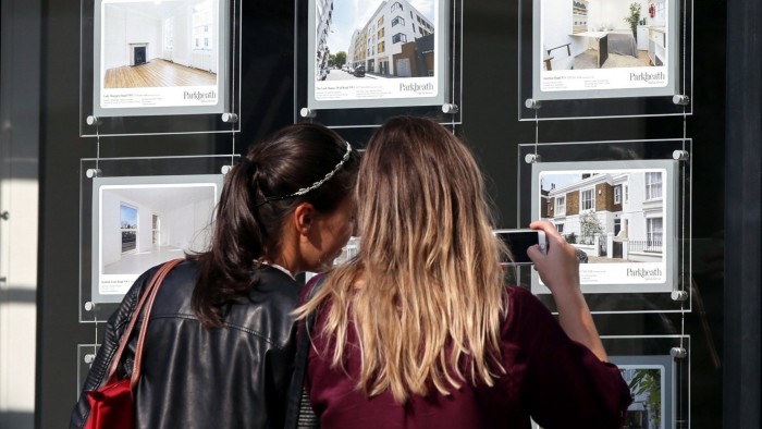 Two women looking at houses in an estate agents window