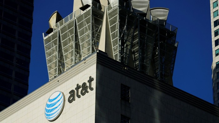 AT&T logo and name displayed on the side of a building with communication equipment on the rooftop.