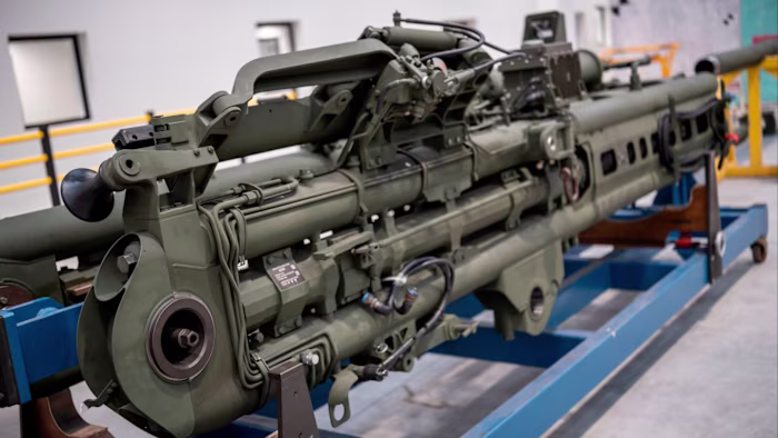 The completed green Howitzer rests on a stand inside a manufacturing facility.