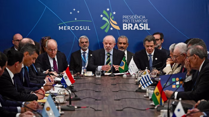 Luiz Inácio Lula da Silva, Mauro Vieira, and Fernando Haddad sit at the center of a conference table during the Mercosur Heads of State Summit.