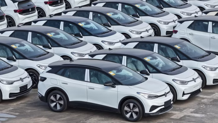 Rows of white Volkswagen electric vehicles with black roofs parked closely together, ready for overseas shipment.