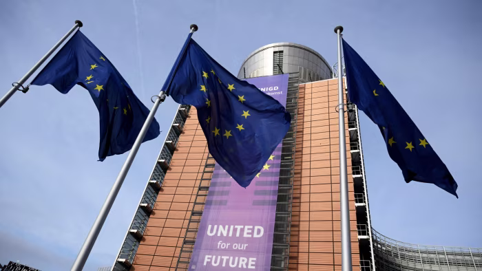 European Union flags flutter in front of the Berlaymont building, with a banner reading “UNITED for our FUTURE” displayed.