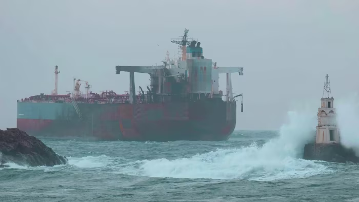 The oil tanker Kairos stranded near the Black Sea port of Ahtopol, with waves crashing against a lighthouse in the foreground.