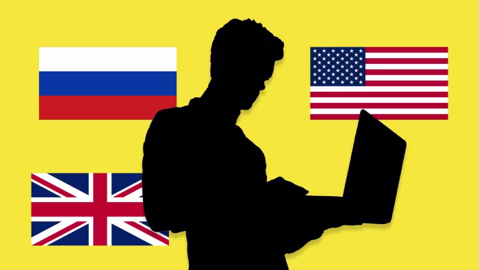 Silhouette of a person using a laptop, with the flags of Russia, the United States, and the United Kingdom on a yellow background.
