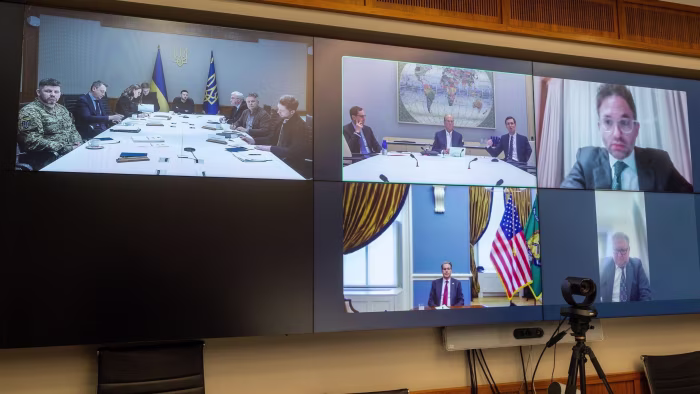 Volodymyr Zelenskyy sits at a conference table with Ukrainian officials, participating in a video call with Scott Bessent, Jared Kushner, and Larry Fink